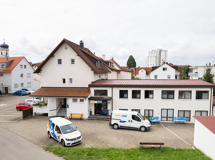 nsicht des Gebäudes der Tettnanger Tafel mit parkenden Lieferwagen und der umliegenden Nachbarschaft