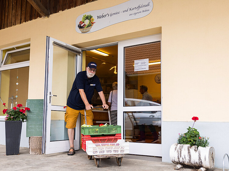 Freiwilliger der Tettnanger Tafel transportiert Kisten mit frischem Gemüse vor einem Laden