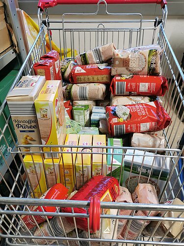 Das Foto zeigt einen Einkaufswagen gefüllt mit gespendeten Lebensmitteln