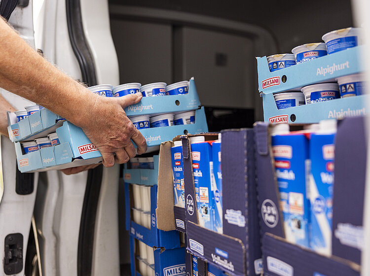 Hand, die Joghurtbecher aus einem Lieferwagen entlädt